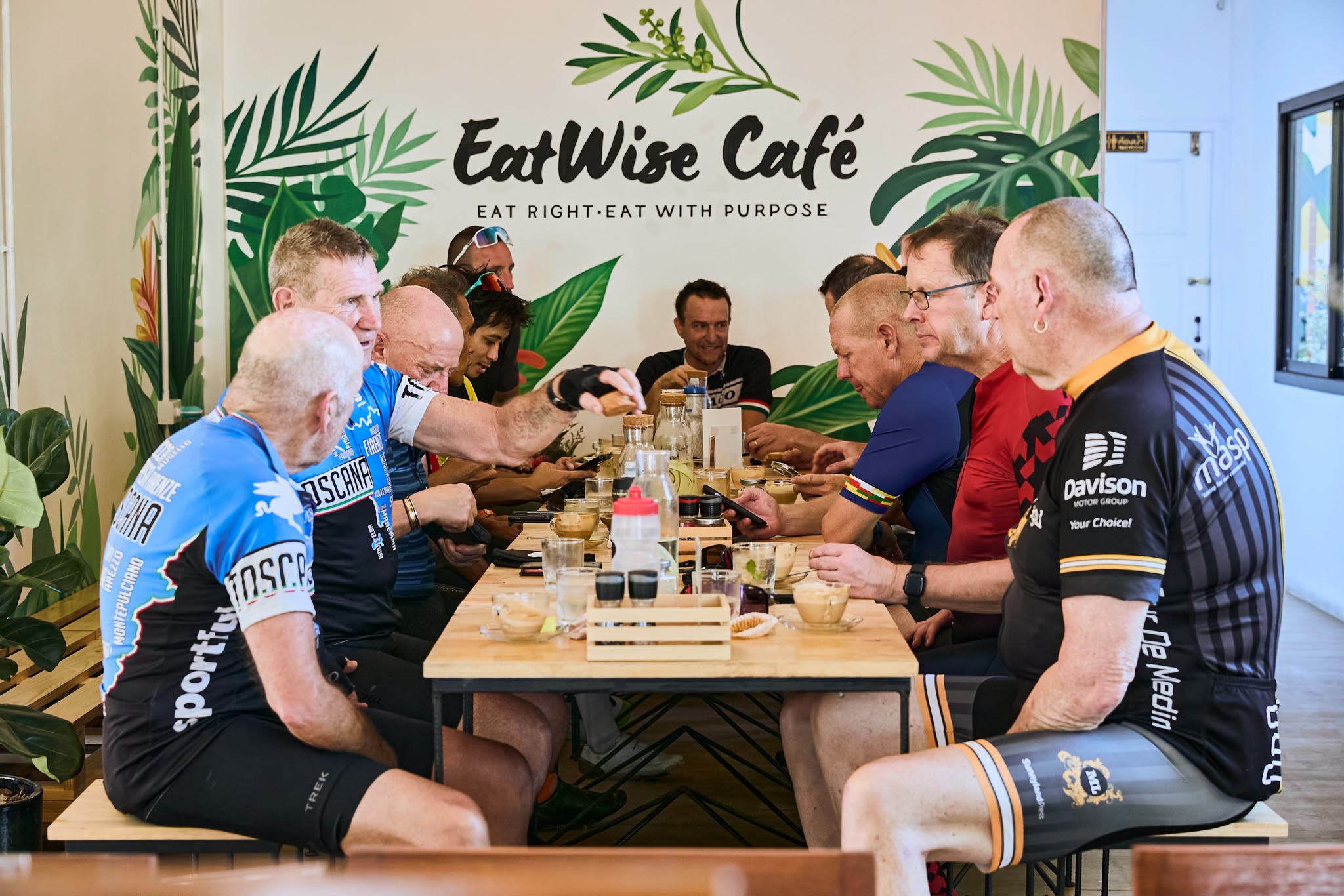 Cycling club enjoying coffee and snacks in front of the café mural