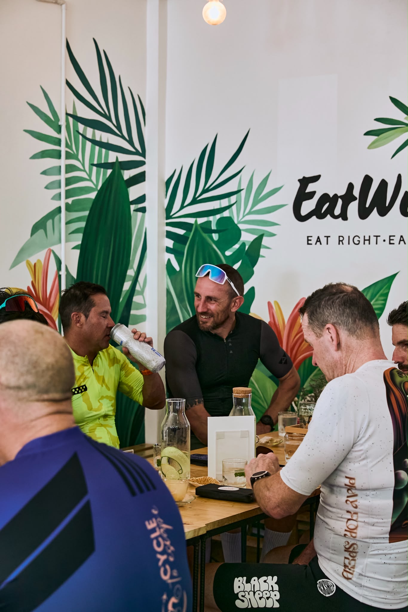 Group relaxing with drinks beneath the EatWise mural