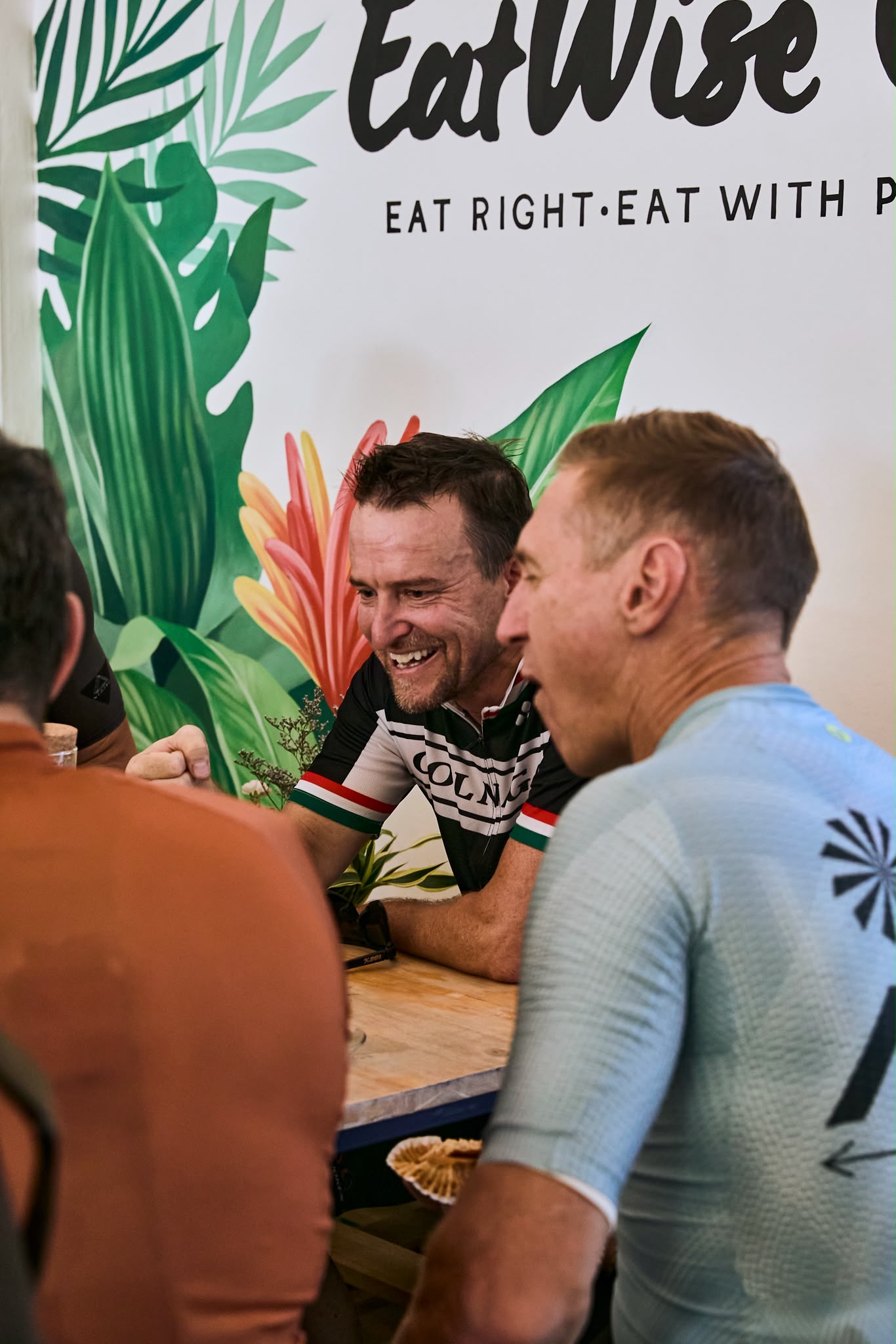 Guests laughing over coffee beneath the tropical wall art