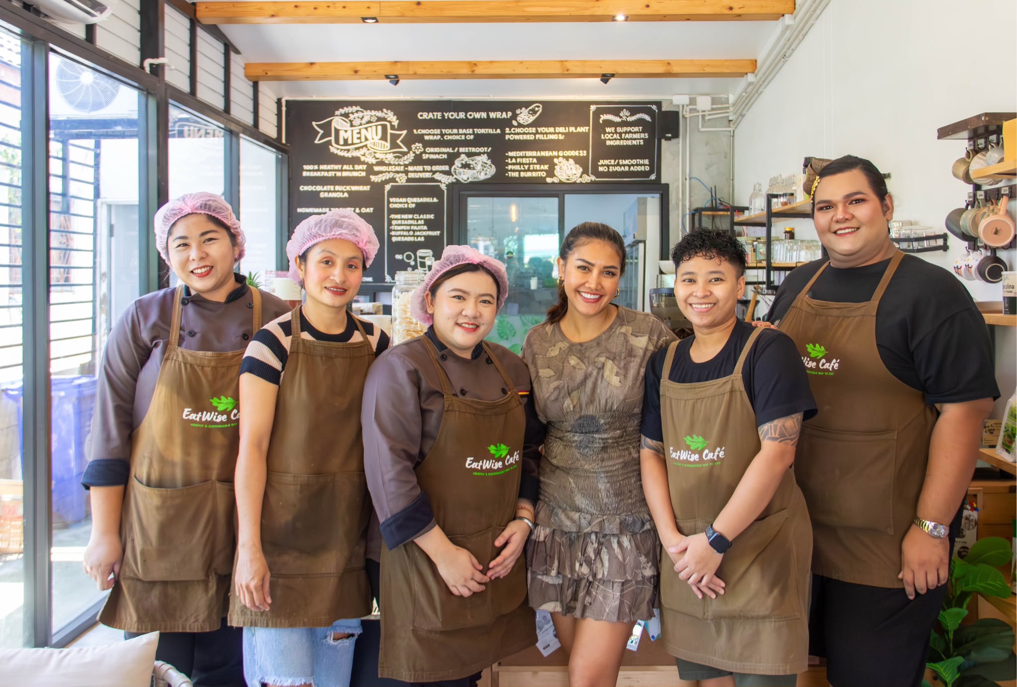 The EatWise Café team with a guest in front of the chalkboard menu
